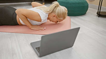 Sporty, attractive and fit young blonde woman staying healthy - stretching back in calm balance...
