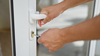 Young hispanic man closing door using key at home - Powered by Adobe
