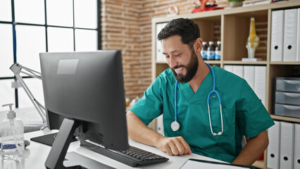 Young hispanic man doctor using computer working at the clinic