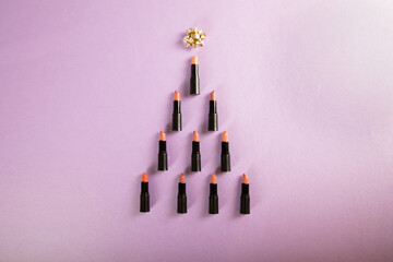 Christmas tree made of lipsticks on purple background