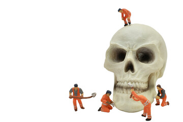 miniature figurines of a men at work team with a huge human skull isolated on white background