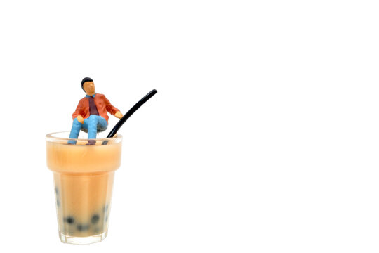 miniature figurine of a young man sitting on a glass of smoothie