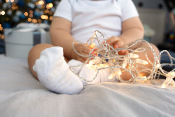 1 year old baby boy plays with garland. New Year Eve and Merry Christmas holiday
