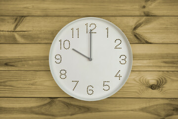 Ten o'clock. Time management or business concept. Plain white wall clock showing 10 am on a wooden background. Copy space. Opening or closing hours. Schedule or working, study hours.