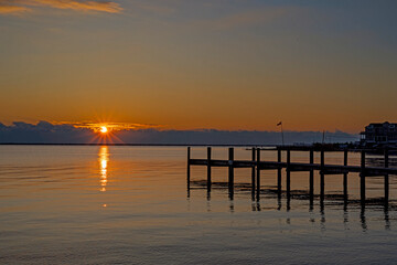 Obraz premium A Dock And Flag On Bay At Sunrise Time In NJ