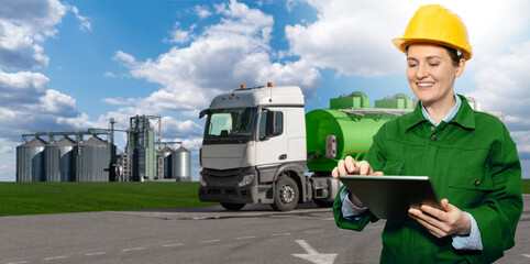 Woman with digital tablet on a background of truck with a tank with biofuel