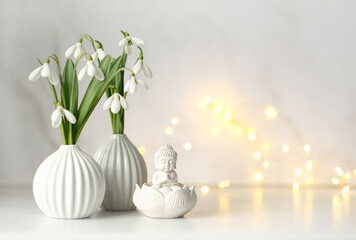 Snowdrop flowers and little Buddha statue on table, abstract light background. spring season....
