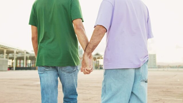 Close-up of a gay couple walking holding hands together. Young unrecognisable gay couple walking hand in hand. Valentine's Day
