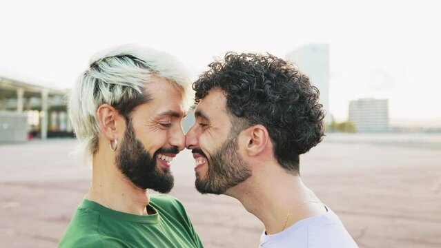 Happy gay couple hugging and touching nose tips in daylight. Slow motion of a young gay couple in love playfully hugging each other with a smile. Valentine's Day
