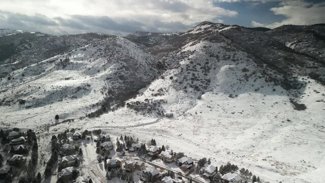 Aerial of snowy homes and mountain in neighborhood in Littleton Colorado against foothills in winter