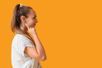 Teenage girl pointing at hearing aid on yellow background