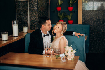 Bride and groom drinking coffee at cafe after their wedding. Posing and embracing newlyweds.
