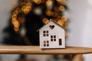 The house is made of felt on the background of Christmas tree lights. Concept photo