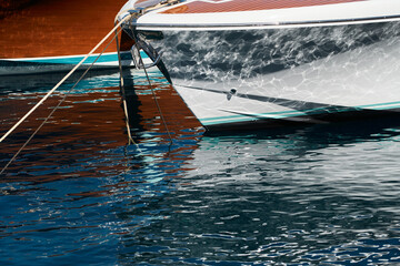 Sun glare on glossy board boats, azure water, tranquillity in port Hercules, bows of moored boats...