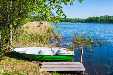 Fishing boat at wooden pier by small lake in Suwalski Landscape Park, Podlasie, Poland