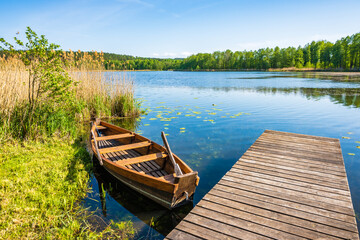 Fishing boat at wooden pier by small lake in Suwalski Landscape Park, Podlasie, Poland