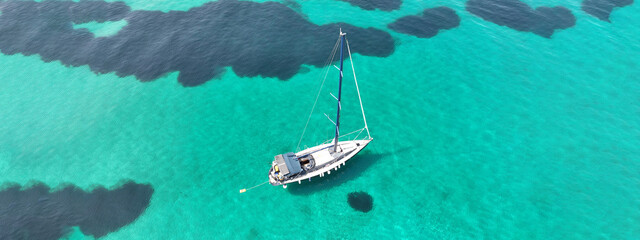 Aerial drone ultra wide panoramic photo of beautiful sail boat with white sails anchored in tropical exotic bay with emerald clear sea - Powered by Adobe