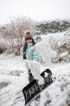 Mädchen, 9 Jahre, mit Schneeschaufel im Freien