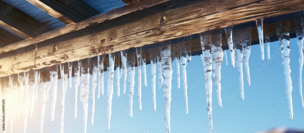 Poster close up icicles hanging from the waves of the roof. copy space image. place for adding text