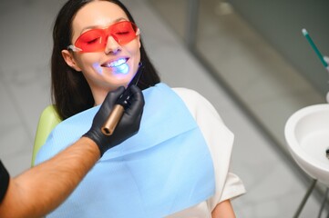 Young woman getting dental filling drying procedure with curing UV light at dental clinic