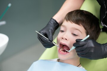 Cute boy smiling while teeth exam . Happy boy sitting in dentists chair and having check up teeth