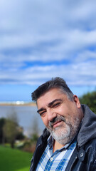 bearded man taking a selfie with the beach in the background and copy space