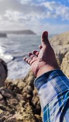 open hand towards the sky in the middle of a sea cliff with waves concept grandeur with copy space