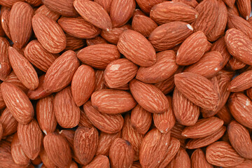 A pile of raw almonds, The almonds are brown and have a rough texture. They are a healthy snack or addition to a meal.