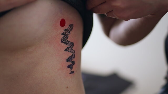 Naked woman enjoying tattoo at home closeup. Unknown girl hand lifting top
