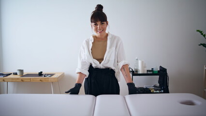 Happy tattooist posing at studio portrait. Smiling woman looking camera closeup
