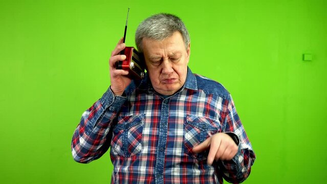 Senior man listening to music on vintage radio.