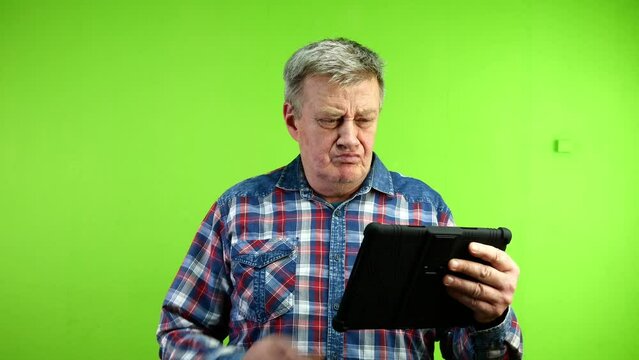 Senior caucasian man looks at tablet and pointing.