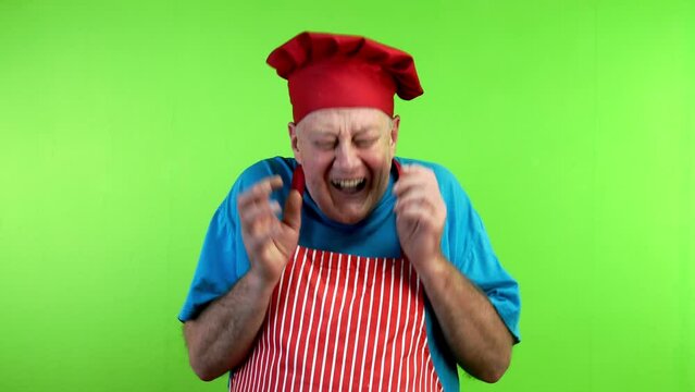 Senior cook in apron laughing over funny joke.