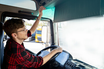 Young truck driver activating tachometer , sitting in truck cabin , ready to go 