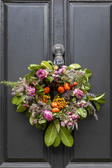 A Christmas wreath of dried red roses, faux pumpkins, dill sprigs, seeds, laurel branches, dried...