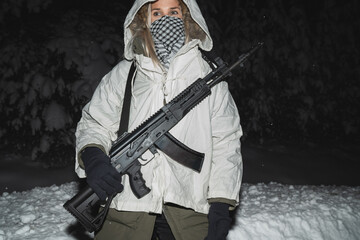 A girl soldier in winter camouflage with an AK 12 assault rifle on a belt near the chest.