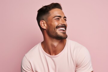 Handsome young man laughing and looking away while standing against pink background