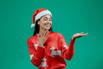 Portrait of happy attractive young woman wearing red sweater posing isolated on green background. Happy New Year celebration merry holiday concept