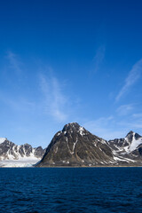 Dramatic clouds in the sky above the mountain peaks in Smeerenburg Fjord, Svalbard, in the summer arctic
