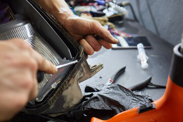 Car headlight in repair close-up. The car mechanic installs the lens in the headlight housing. The...
