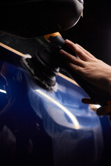 Car detailing - Man with orbital polisher in repair shop polishing car. Selective focus