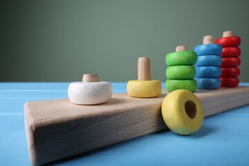 Stacking and counting game pieces on light blue table against grey wall, closeup. Motor skills...