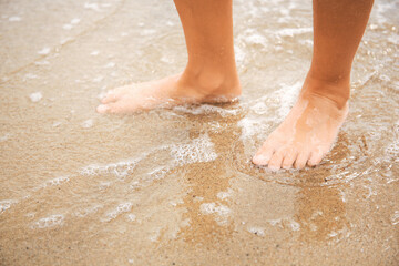 Little girl in water on sandy beach, closeup. Space for text