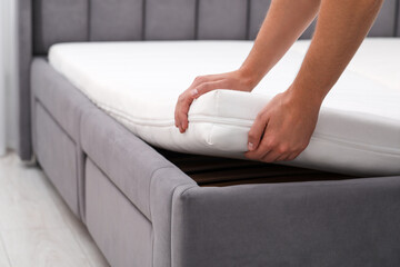 Man putting soft mattress on bed, closeup