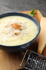 Delicious cream soup with parmesan cheese and croutons in bowl on table