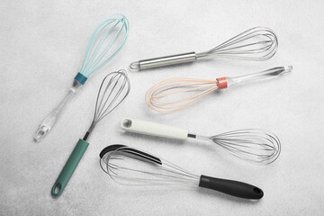 Different whisks on gray table, flat lay