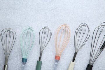 Different whisks on gray table, flat lay. Space for text