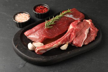 Pieces of raw beef meat and spices on grey textured table