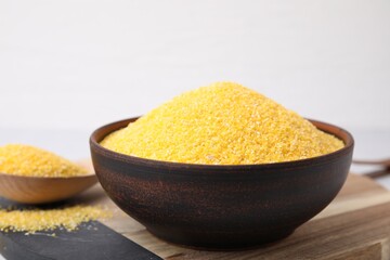 Raw cornmeal in bowl on table, closeup