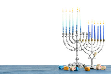 Hanukkah celebration. Menorahs and dreidels on blue wooden table against white background